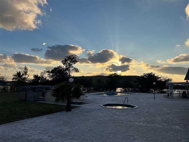 yard at dusk featuring a community pool and a patio area