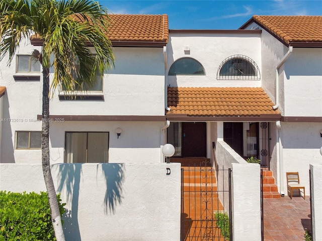 view of front of property with a fenced front yard, a tile roof, a gate, and stucco siding