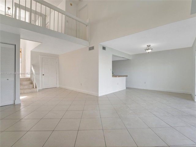 interior space featuring stairway, baseboards, light tile patterned floors, and visible vents