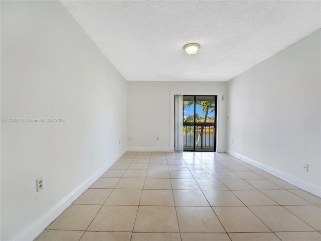 unfurnished room featuring light tile patterned flooring, a textured ceiling, and baseboards