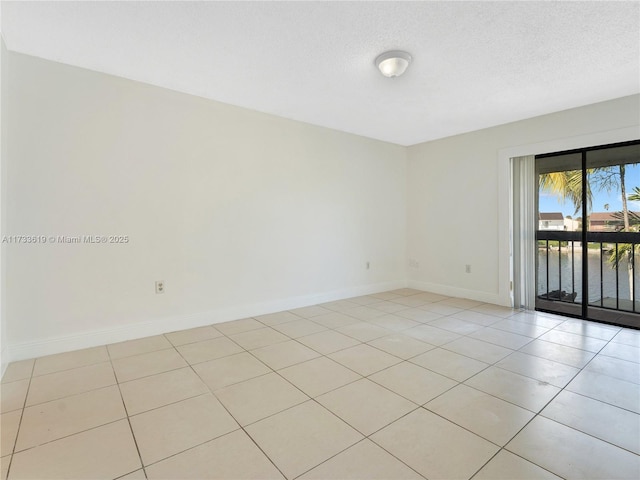 unfurnished room featuring a textured ceiling, a water view, light tile patterned flooring, and baseboards