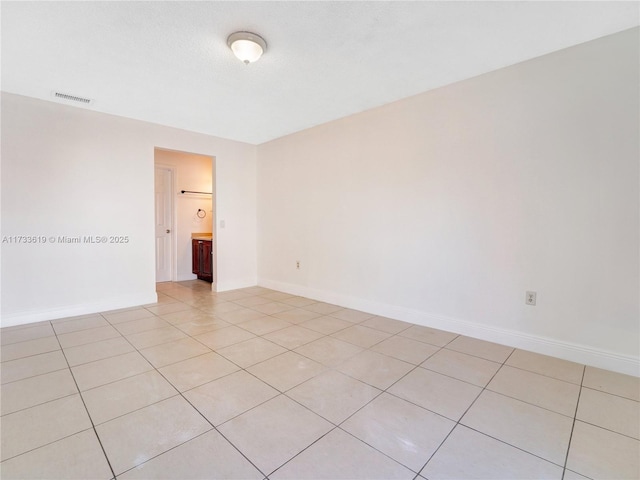 spare room with light tile patterned floors, baseboards, and visible vents