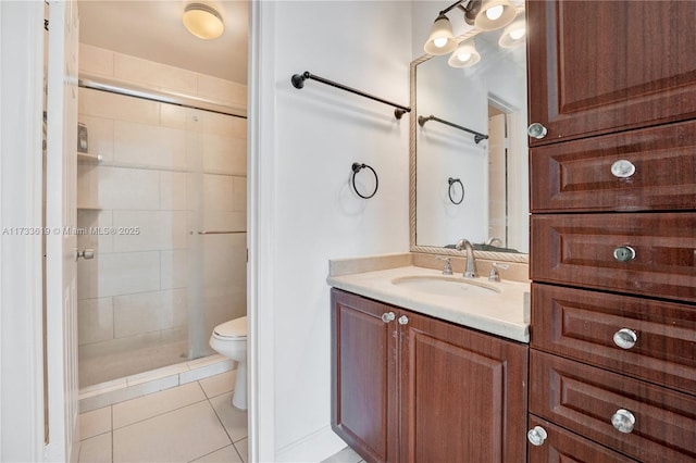 full bath featuring toilet, a shower stall, vanity, and tile patterned floors