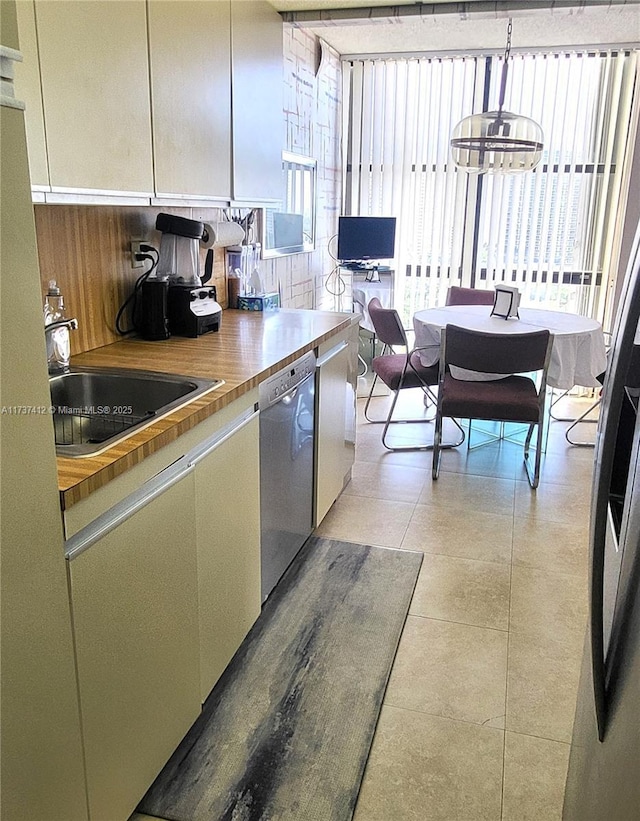 kitchen with a sink, stainless steel dishwasher, and light tile patterned floors