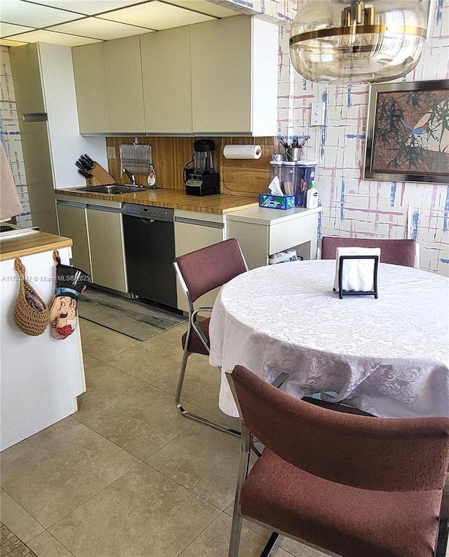 kitchen with black dishwasher, light tile patterned flooring, and a sink