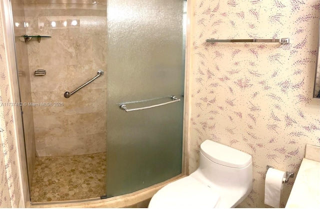 bathroom featuring a stall shower, toilet, and wallpapered walls