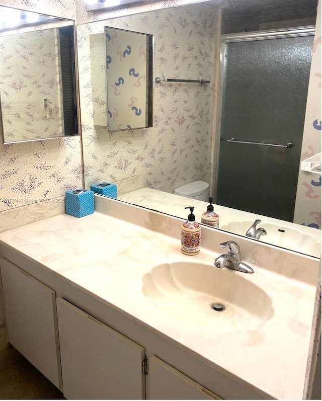 full bath with toilet, a shower stall, vanity, and wallpapered walls