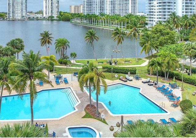 community pool featuring a view of city, a patio, and a water view