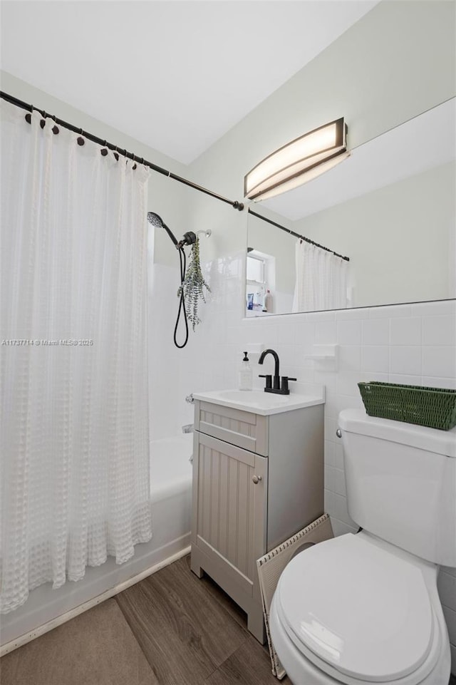 full bathroom featuring tile walls, hardwood / wood-style floors, vanity, shower / bath combination with curtain, and toilet