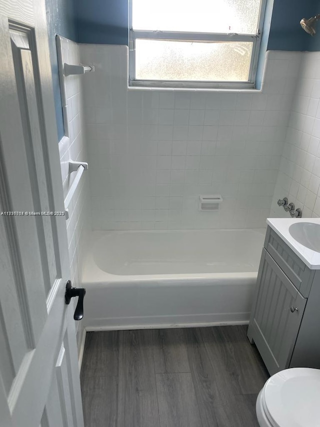 full bathroom featuring wood-type flooring, toilet, tiled shower / bath combo, and vanity