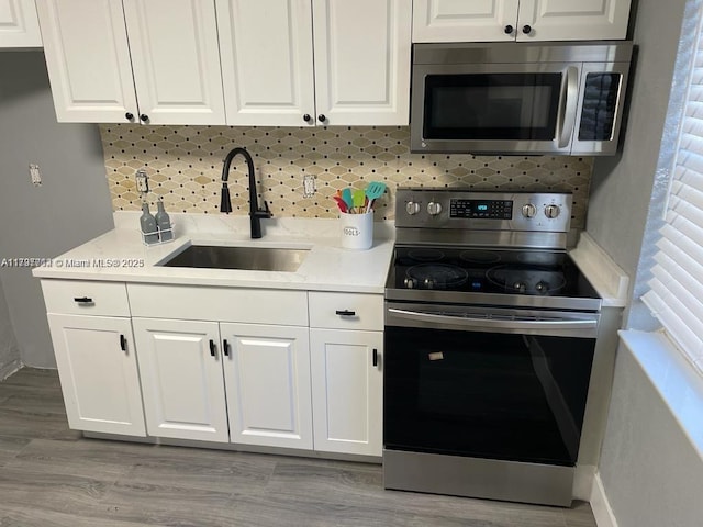 kitchen with stainless steel appliances, sink, decorative backsplash, and white cabinets