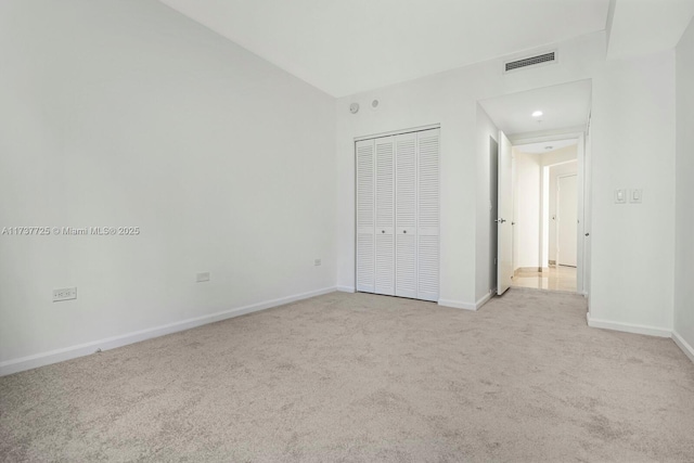 unfurnished bedroom featuring light carpet and a closet