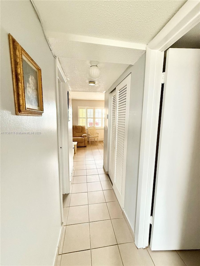 hallway featuring light tile patterned floors and a textured ceiling