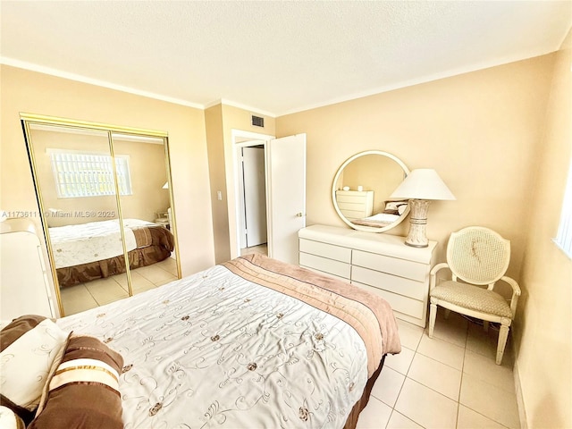 bedroom with crown molding, light tile patterned floors, a textured ceiling, and a closet