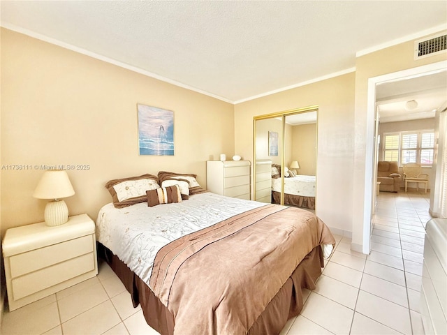 bedroom featuring light tile patterned floors, crown molding, a closet, and a textured ceiling