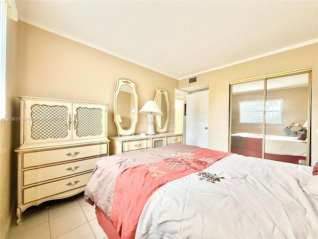 bedroom with light tile patterned flooring, crown molding, and a closet