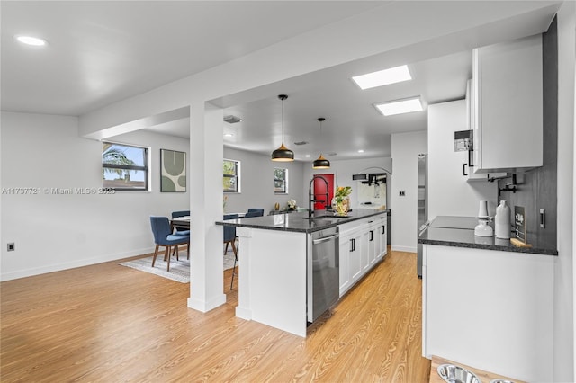 kitchen with sink, dishwasher, white cabinetry, a kitchen island with sink, and decorative light fixtures