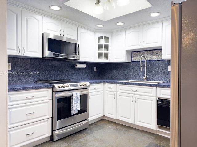 kitchen featuring dark countertops, white cabinetry, appliances with stainless steel finishes, and a sink