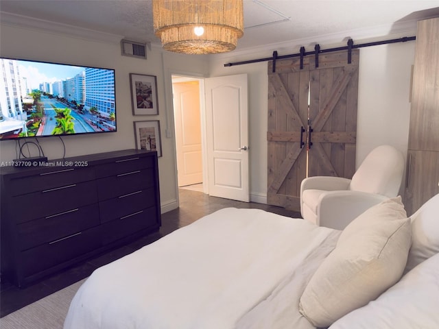 bedroom featuring baseboards, a barn door, visible vents, and crown molding