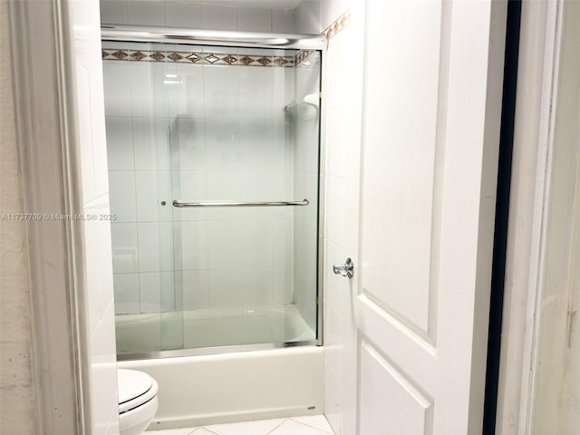 bathroom featuring enclosed tub / shower combo, toilet, and tile patterned floors