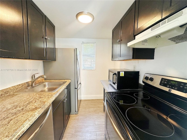 kitchen with sink, light hardwood / wood-style flooring, appliances with stainless steel finishes, dark brown cabinets, and light stone counters