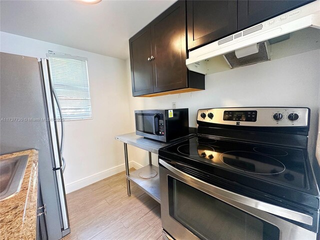 kitchen featuring dark brown cabinetry, stainless steel appliances, and light wood-type flooring