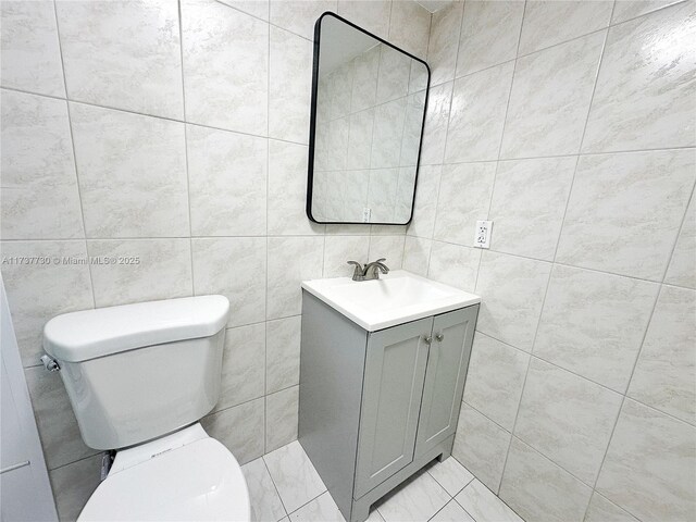 bathroom featuring vanity, tile walls, and toilet