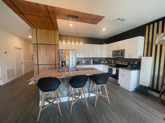 kitchen featuring pendant lighting, white cabinetry, stainless steel appliances, and a center island