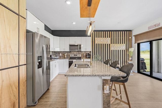 9049 Green Cir, La Belle, FL 33935 - kitchen featuring decorative backsplash, light wood finished floors, a breakfast bar, appliances with stainless steel finishes, and a sink