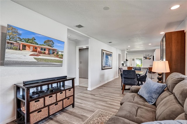 living room featuring a textured ceiling and light wood-type flooring