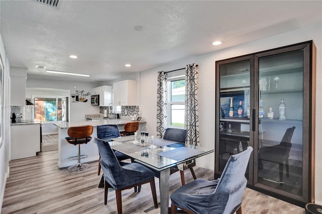 dining space with a textured ceiling and light hardwood / wood-style flooring