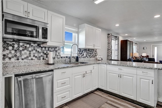 kitchen with stainless steel appliances, kitchen peninsula, sink, and white cabinets