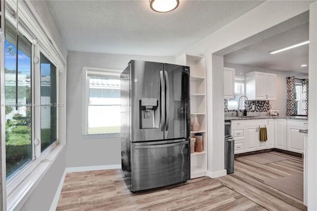 kitchen featuring light wood-type flooring, stainless steel fridge, sink, and white cabinets