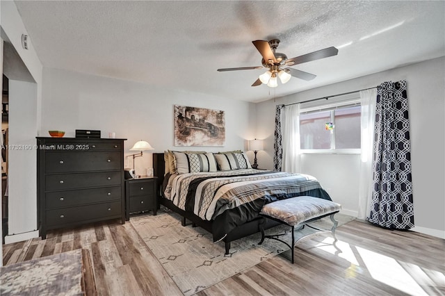 bedroom featuring ceiling fan, a textured ceiling, and light hardwood / wood-style floors