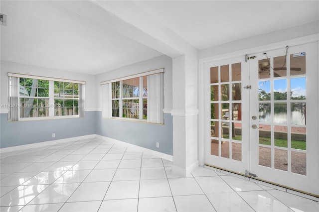 tiled spare room featuring a water view and french doors