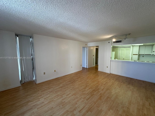 unfurnished living room featuring track lighting, a textured ceiling, and light hardwood / wood-style floors