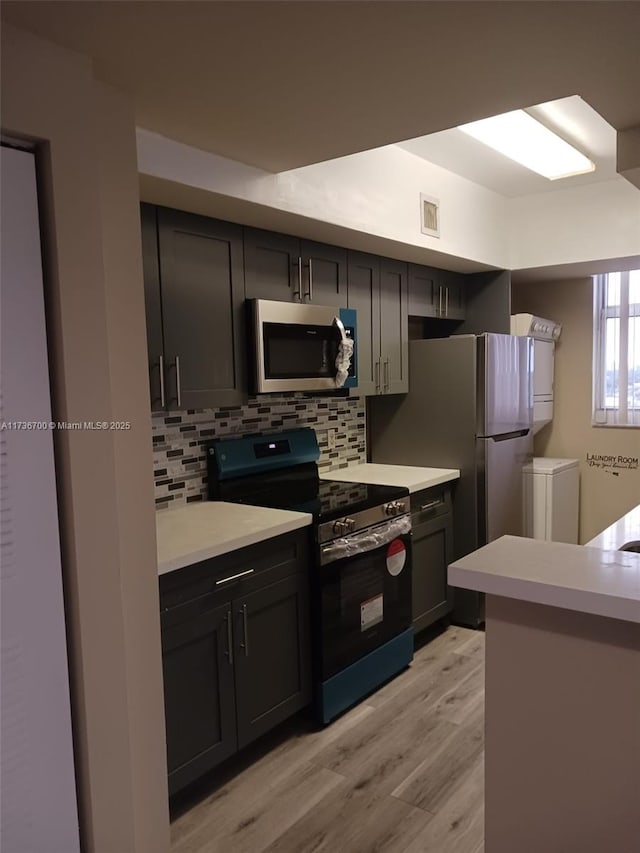 kitchen with backsplash, electric range, and light hardwood / wood-style flooring