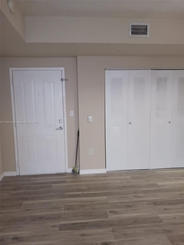 unfurnished bedroom with wood-type flooring, a textured ceiling, and a closet