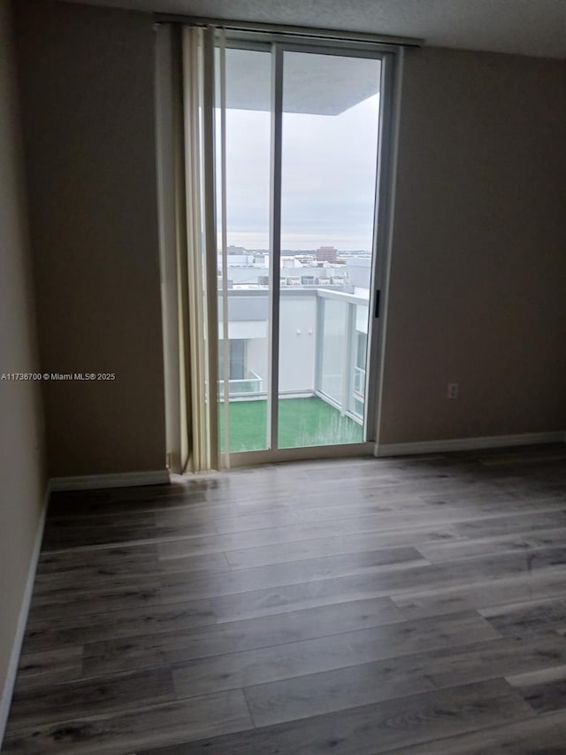 unfurnished room featuring dark wood-type flooring and a wall of windows