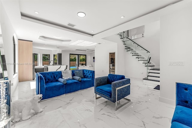 living room with french doors, a tray ceiling, and sink