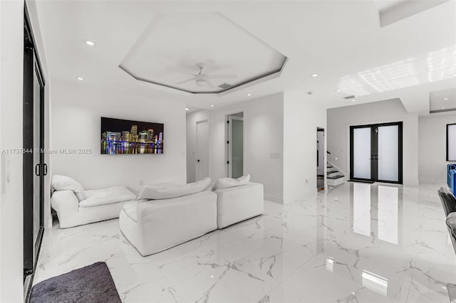 living room with french doors, ceiling fan, and a raised ceiling