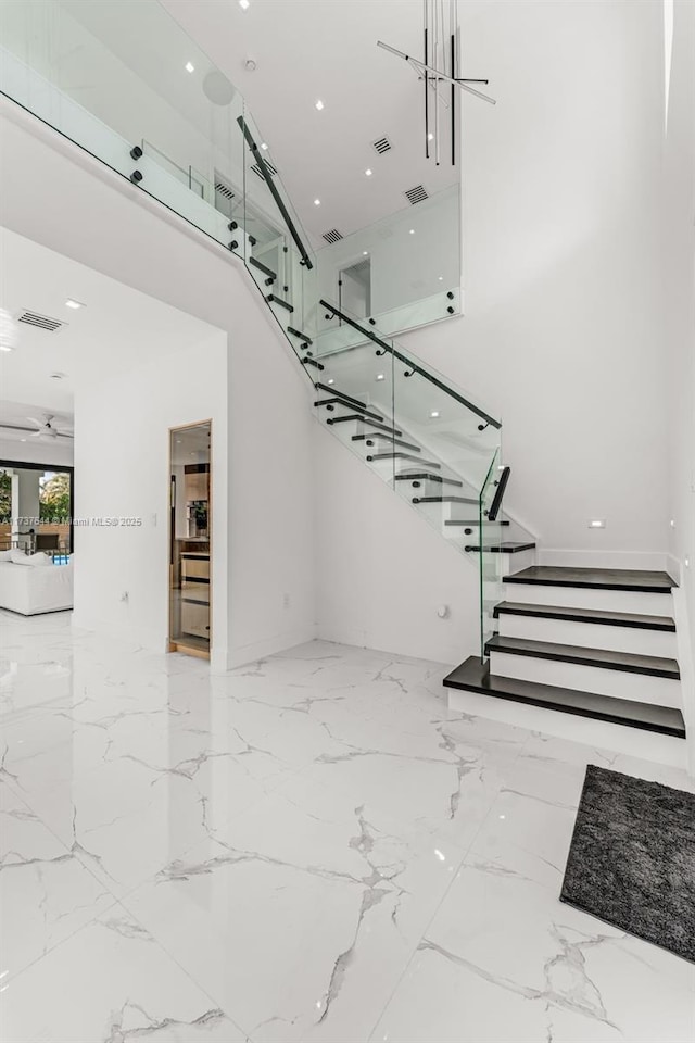 stairway featuring a high ceiling and ceiling fan