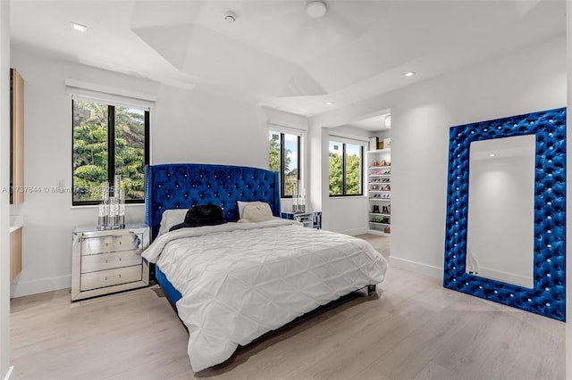 bedroom with multiple windows and light hardwood / wood-style flooring