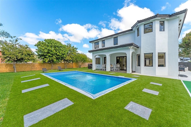 rear view of house with a yard, a fenced in pool, and a patio area