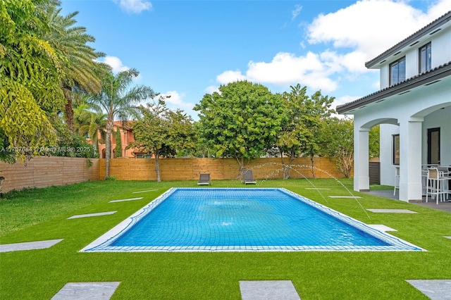 view of swimming pool featuring pool water feature and a yard