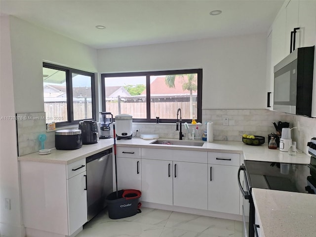 kitchen with tasteful backsplash, stainless steel appliances, sink, and white cabinets