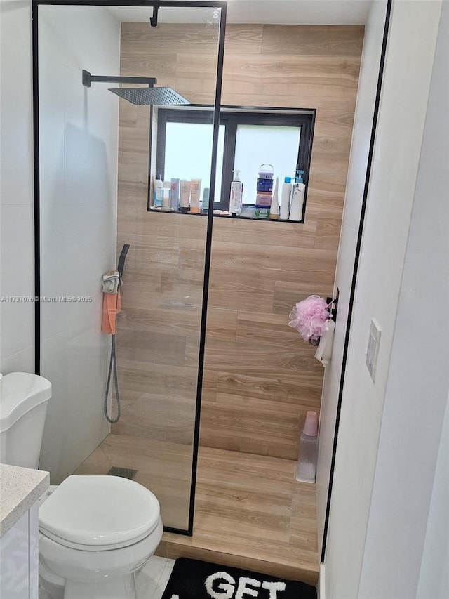 bathroom featuring vanity, a tile shower, and toilet