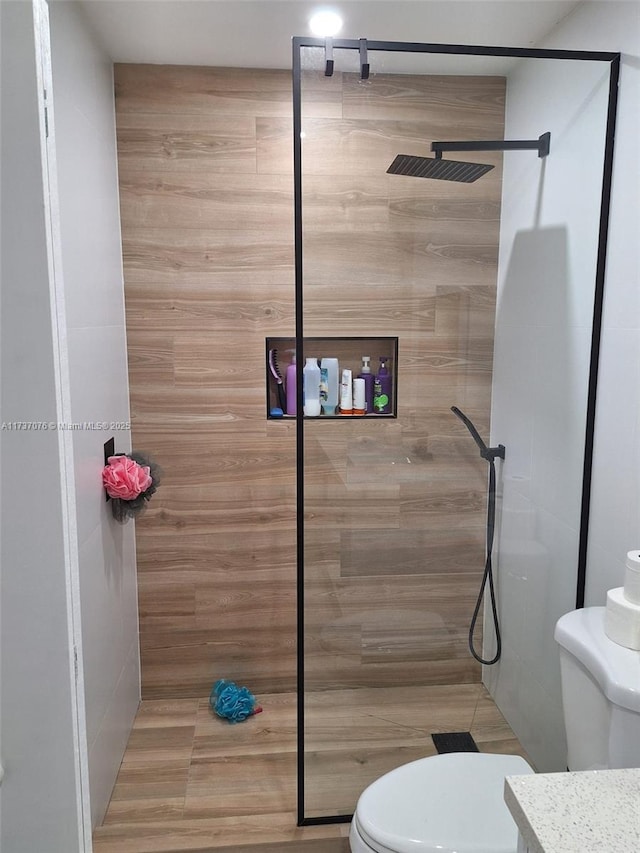 bathroom with tiled shower and toilet