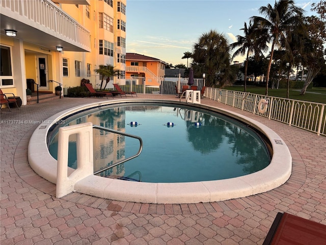 pool at dusk with a patio area