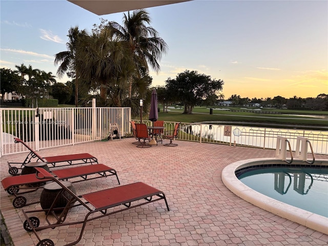 pool at dusk with a patio area